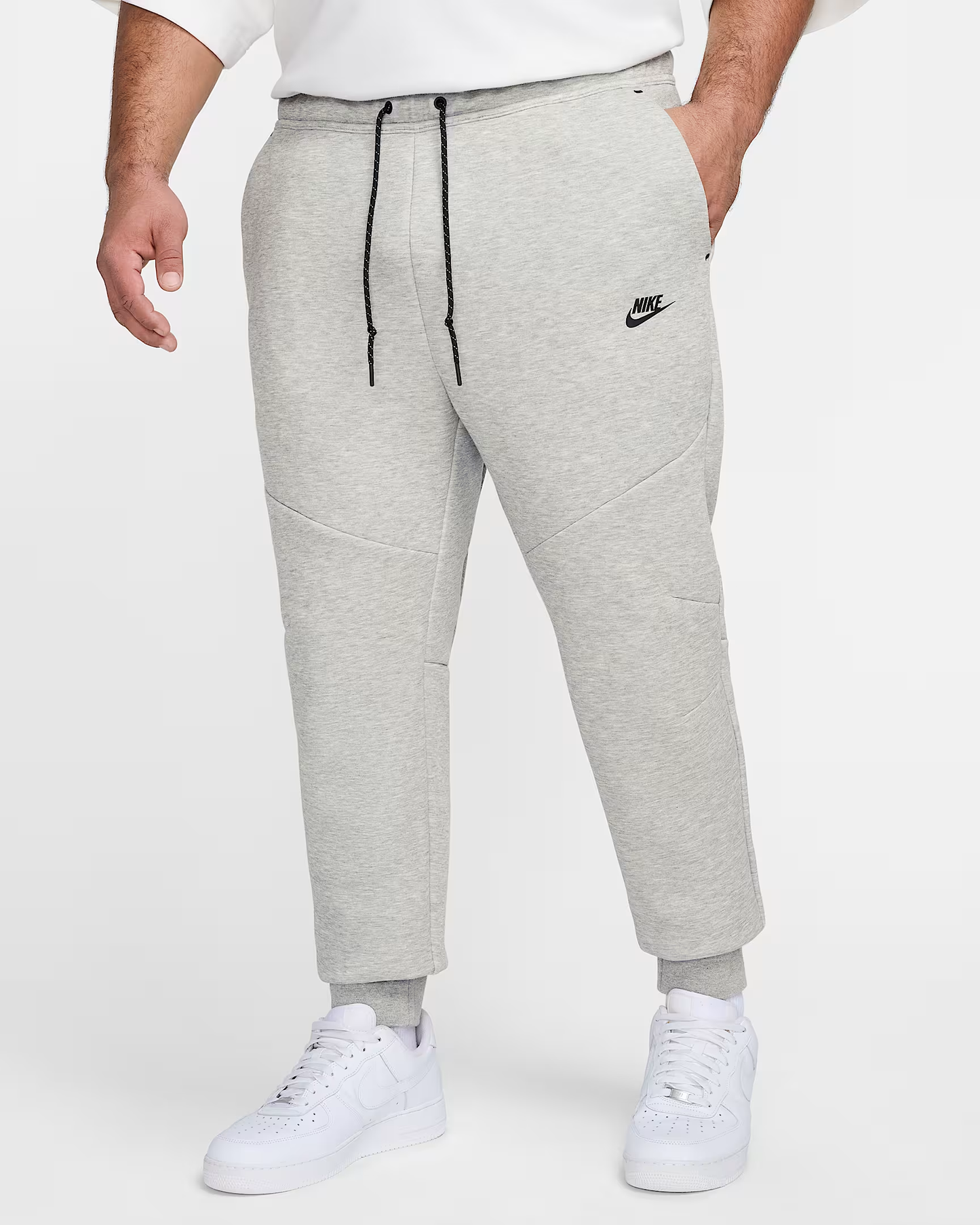 Athletic Grey Nike Mens Tech Fleece Pants, featuring black drawstring, Nike logo, & ribbed cuffs on model.