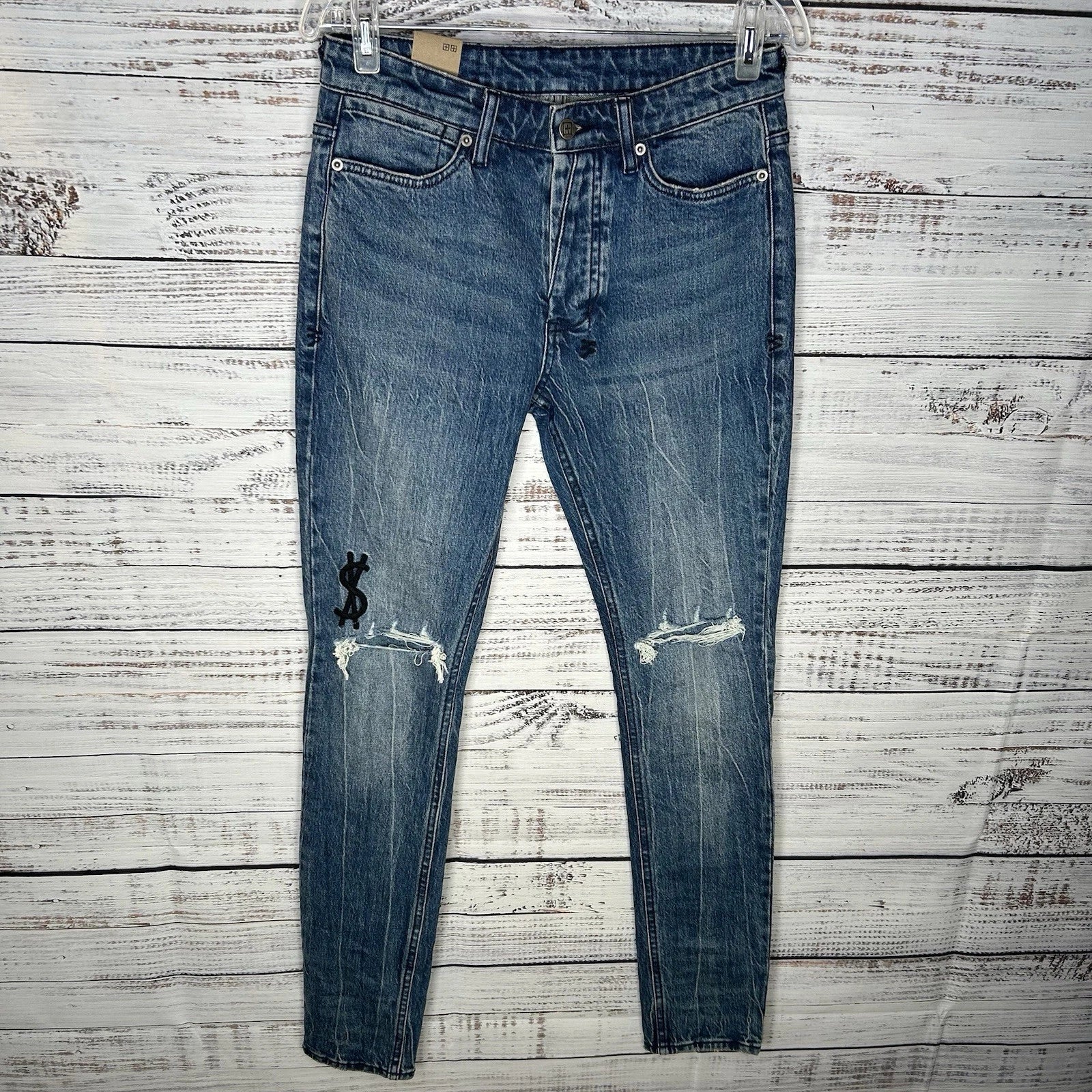 KSUBI unisex blue distressed jeans with ripped knees and $ embroidery.