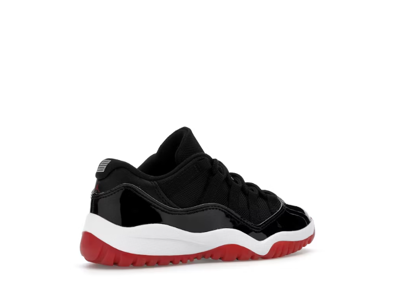 Jordan 11 Retro Low PS Bred black patent leather preschool shoe with red sole, 3/4 view.