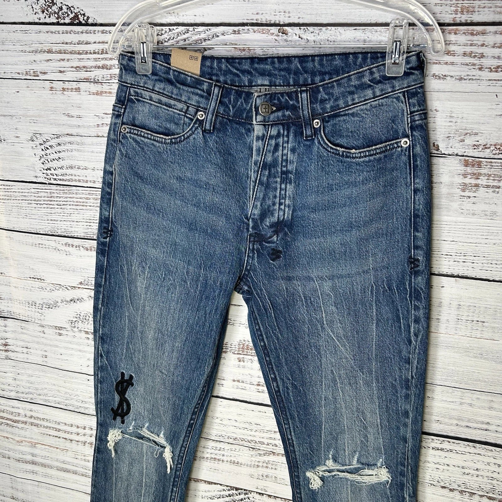 Ksubi unisex distressed blue ripped jeans with dollar sign embroidery.