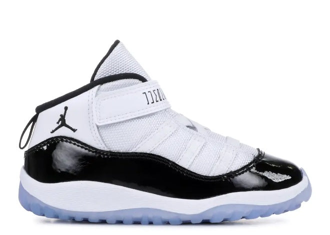 Air Jordan 11 infants black/white sneaker with patent leather, Jumpman logo, and JORDAN velcro strap.