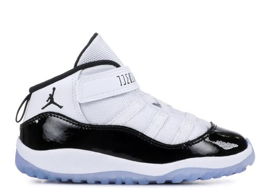 Air Jordan 11 infants black/white sneaker with patent leather, Jumpman logo, and JORDAN velcro strap.