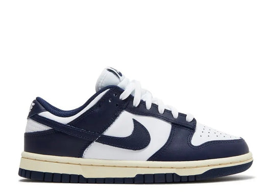 Nike Womens Dunk Low sneakers, white leather with midnight navy overlays and a sail midsole.